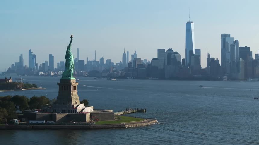 Aerial view of the statue of liberty on an island surrounded by the sea and in the background a metropolis with skyscrapers