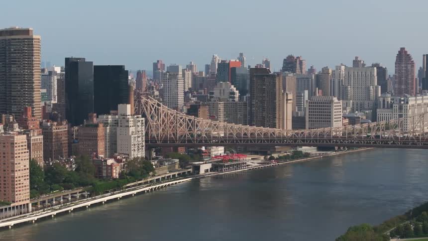 A cityscape with a bridge crossing a body of water featuring tall buildings and a diverse mix of architecture