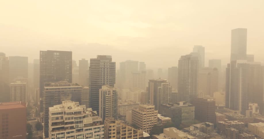 Murky wildfire smoke fills the air and paints the city in surreal tones of orange and brown