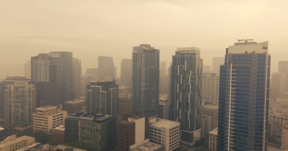 Apartment and office buildings in the city surrounded by thick wildfire smoke