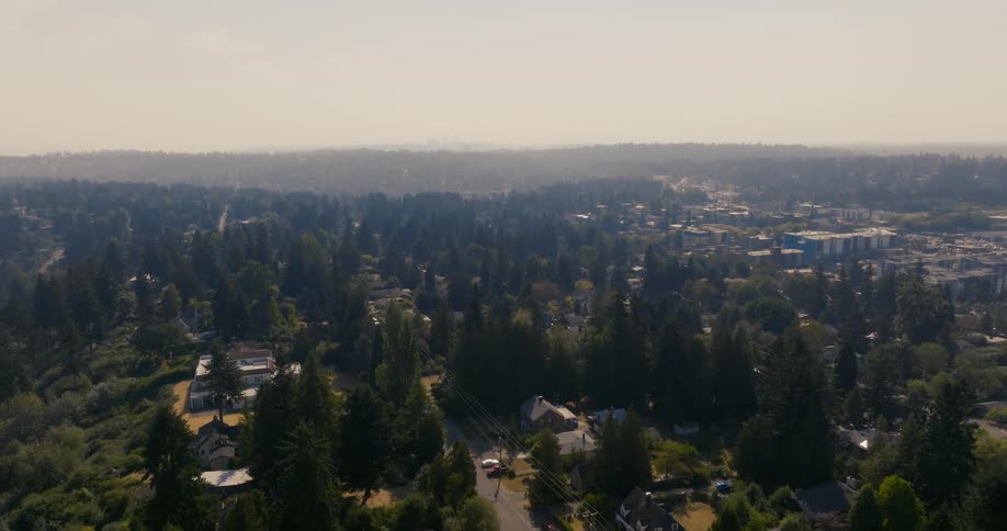 Hazy smoke fills the air above a suburban cityscape with a mix of residential homes and trees