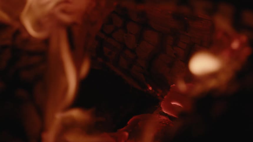 A close up of a bond fire with burning wood and embers