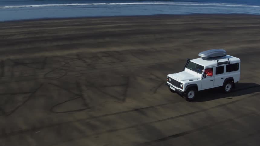 A man drives a white jeep on a beach