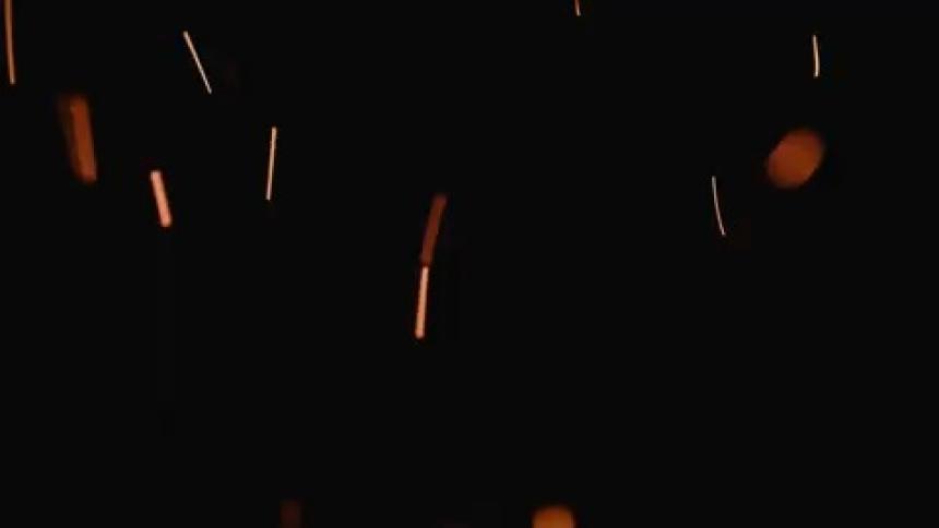 Sparks float up from the fire at night