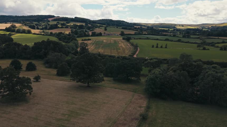 A tranquil rural landscape with rolling hills fields and woodland
