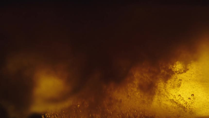 Disturbed amber fluid fizzes and turns cloudy