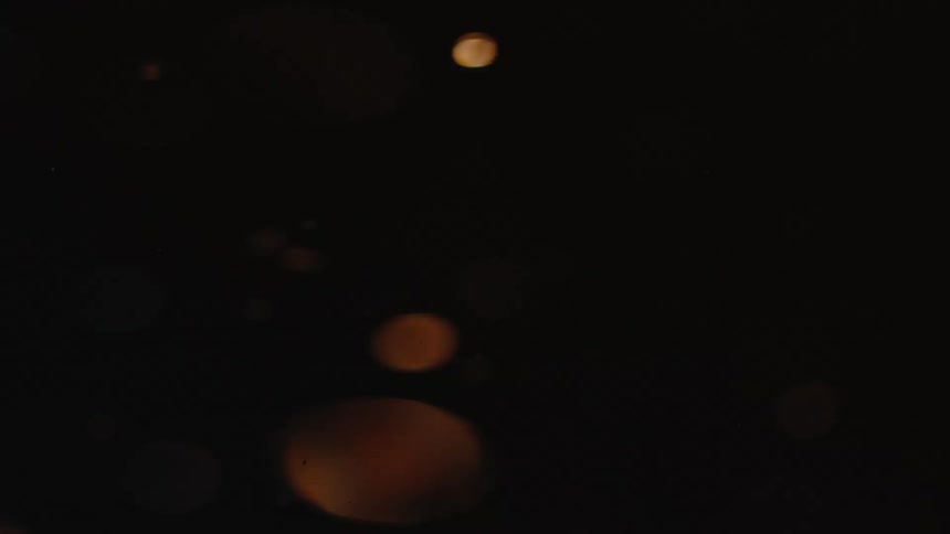 Closeup view of particles floating in a liquid with light reflecting through it creating an amber glow