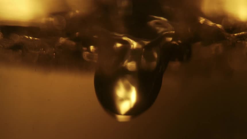Closeup view of a golden brown liquid with light reflecting through it creating an amber glow