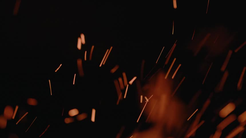 Flames dance and throw off sparks at night