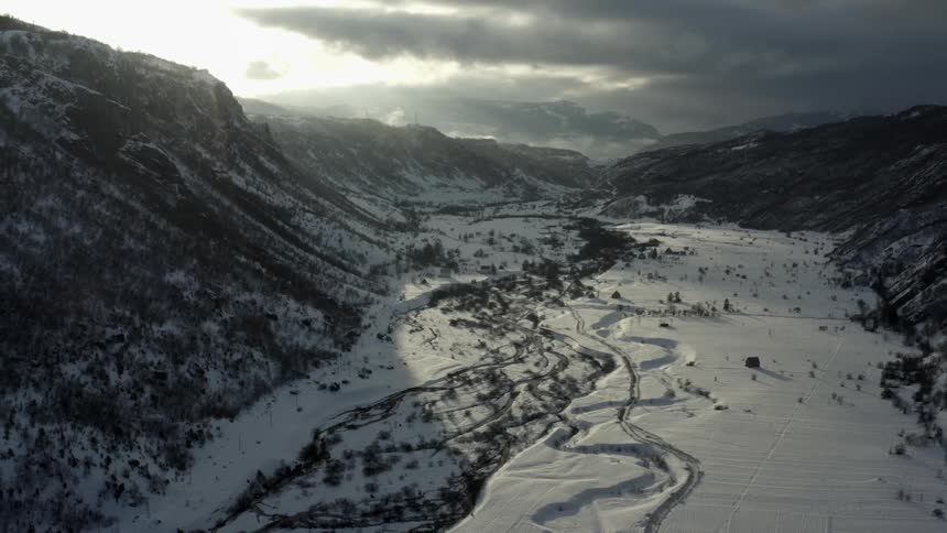 Aerial panorama of snowcovered mountain ranges with vegetation under a stormy sky