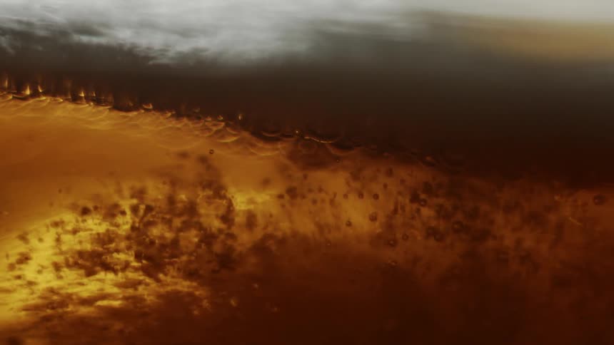 Bubbles rise toward the foam on top of a beer