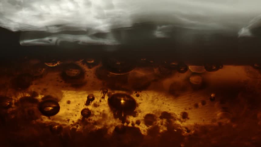 Large and small bubbles of beer rise up to foam