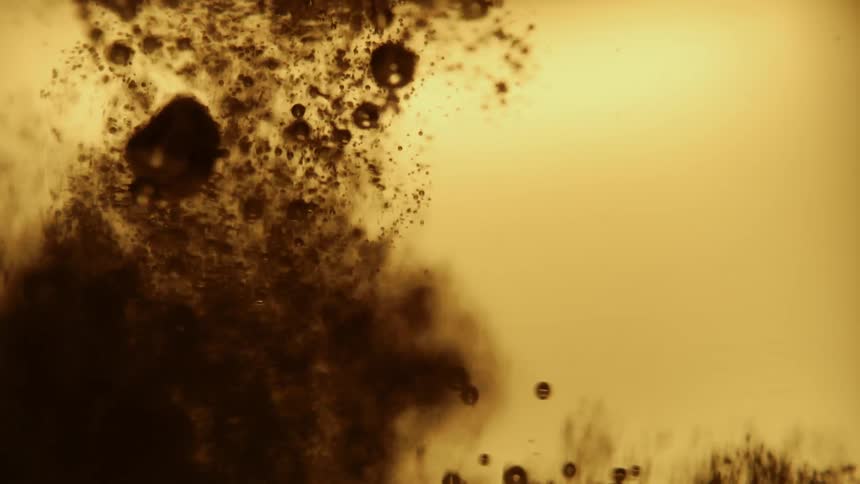 Closeup view of bubbles and foam in a goldenbrown liquid with light reflecting through it creating an amber glow