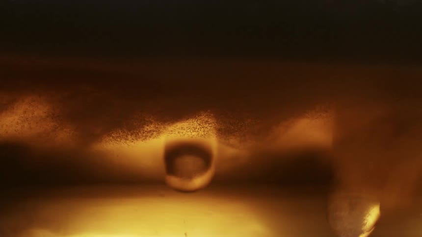 Closeup view of bubbles and foam in a goldenbrown liquid with light reflecting through it creating an amber glow