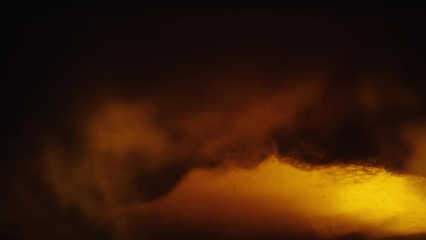 Closeup view of bubbles and foam in a goldenbrown liquid with light reflecting through it creating an amber glow