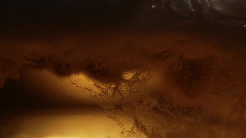 Closeup view of bubbles and foam in a goldenbrown liquid with light reflecting through it creating an amber glow