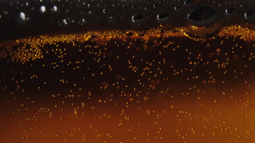 Small amber bubbles rise up in a glass of beer