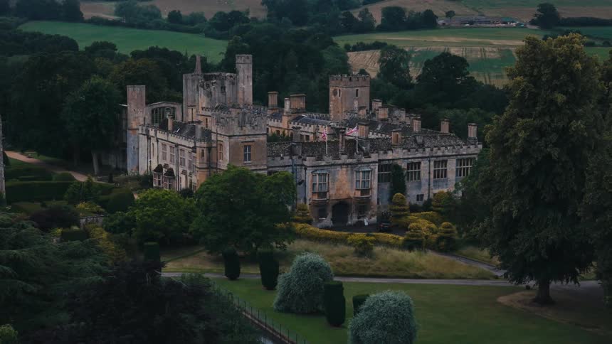 An ornate castle with multiple turrets and windows surrounded by lush vegetation and manicured gardens