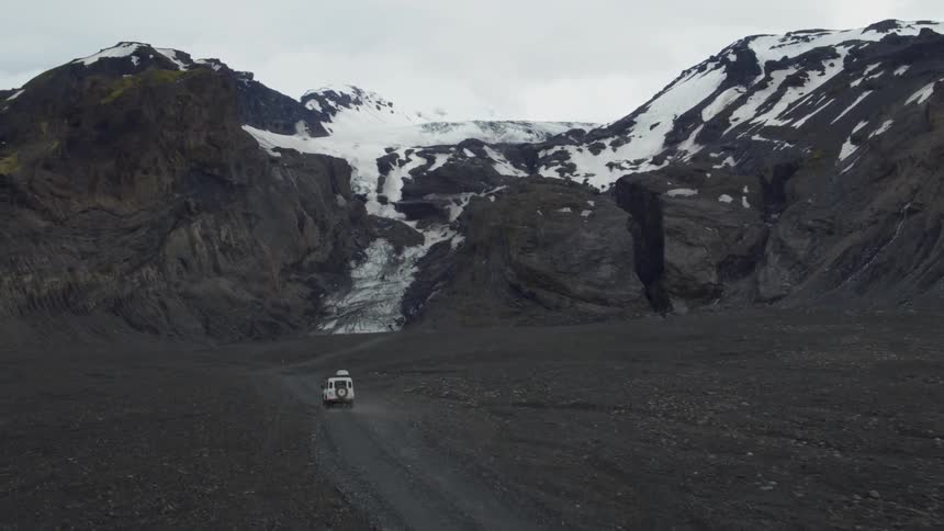 Jeep driving down a gravel road towards mountains