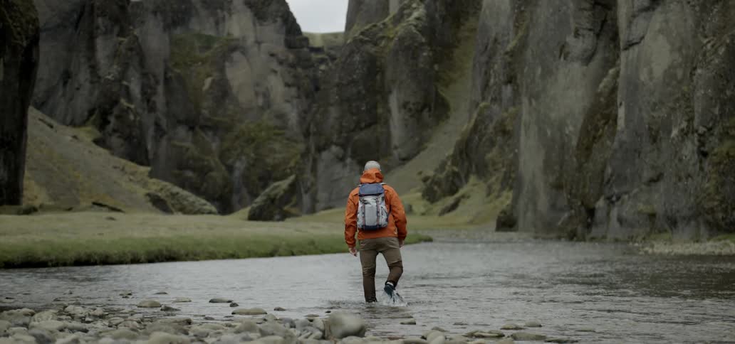 A hiker wades through a canyon river