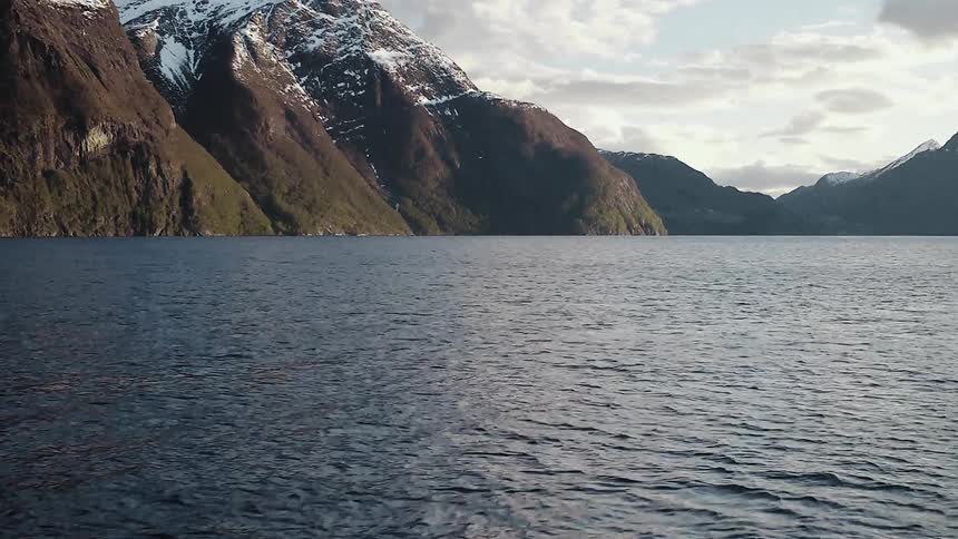 Moving over a large body of water with snow covered peaks up ahead
