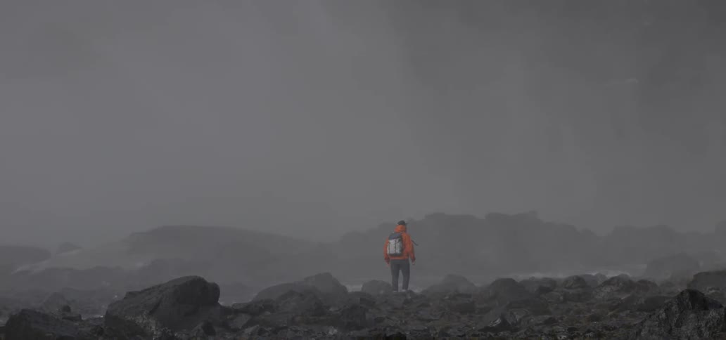 A hiker stands near a misty river