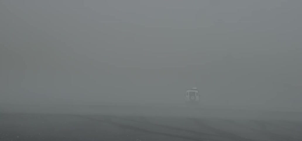 A vehicle drives through the fog