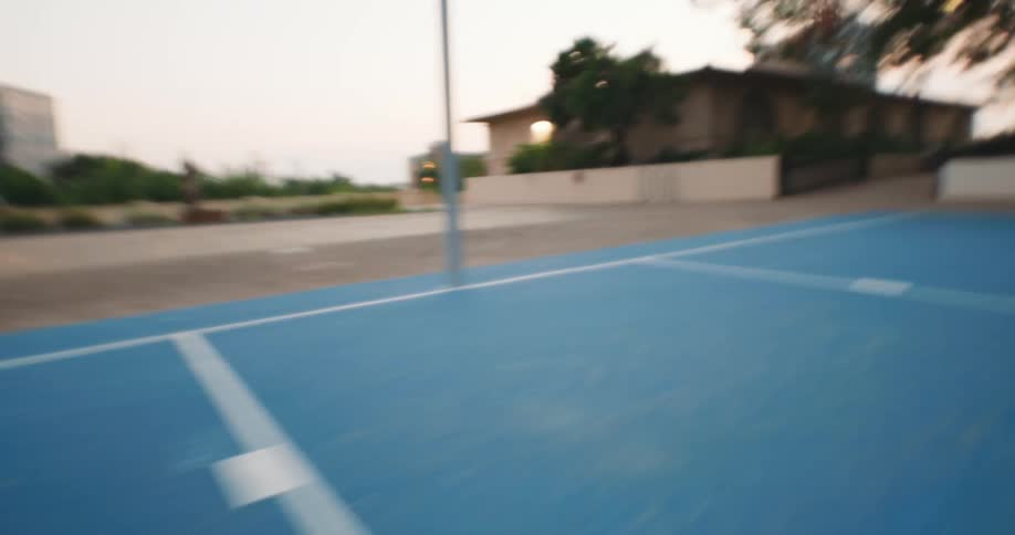 A woman in a wheelchair is playing basketball and she hits the basket on a court with blue paint on the floor