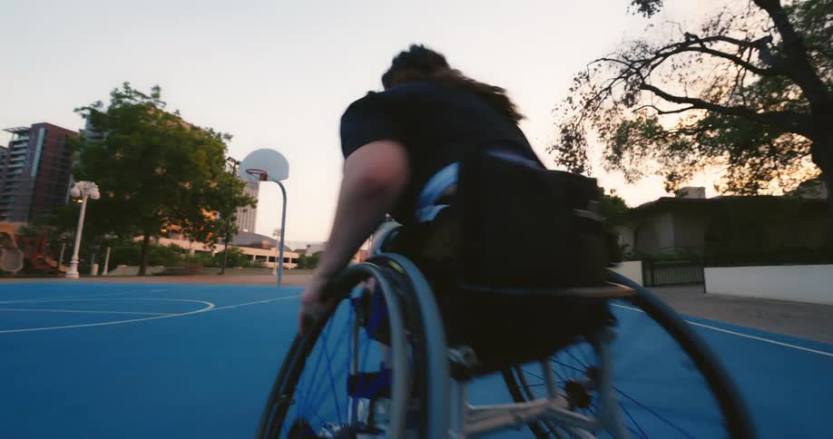 A teenage girl playing basketball by herself in a park shooting the ball at the hoop
