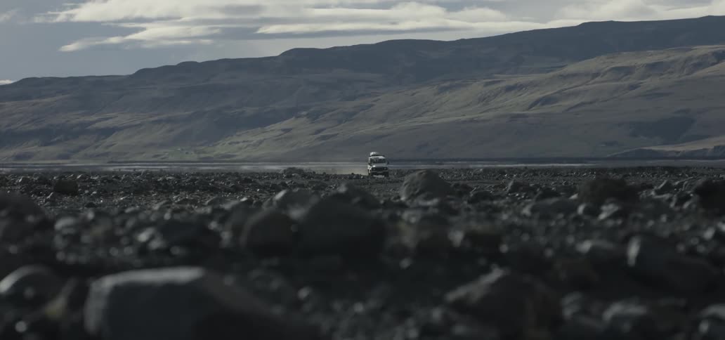 Jeep driving down an abandoned road near hills