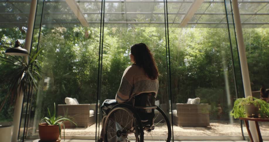 A young woman sits in a wheelchair inside of a house