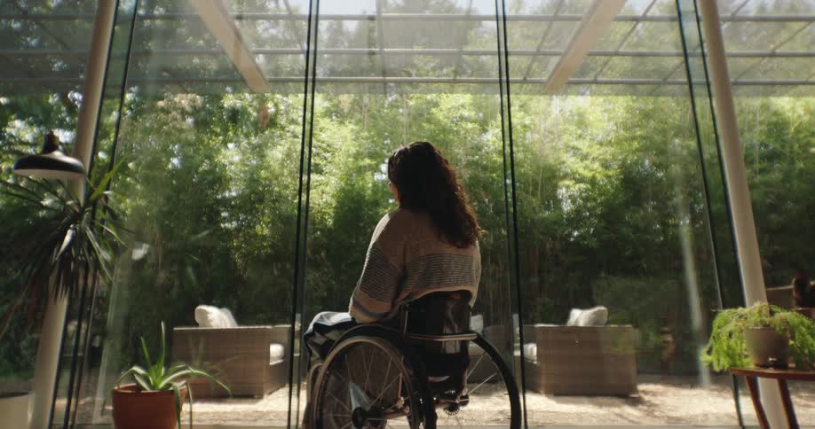 A woman in a wheelchair looking out into a garden