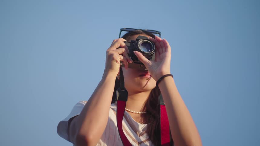 An asian woman takes a photograph while outdoors