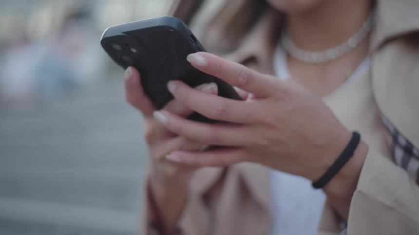 A female human hand holding a cellphone with a black cover