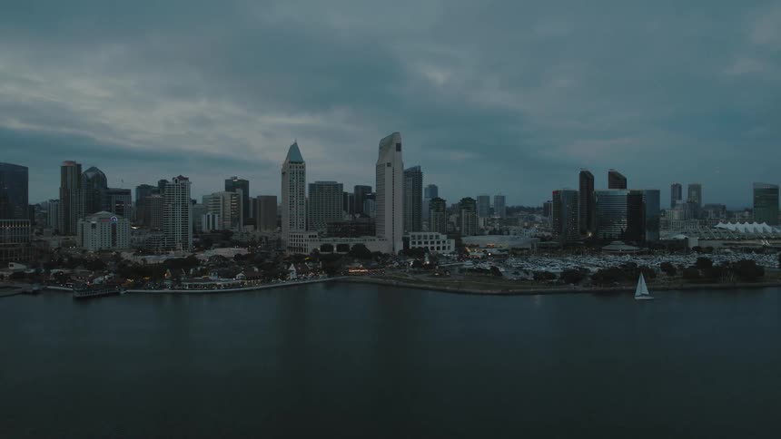 A boat sails past the downtown San Diego skyline at blue hour
