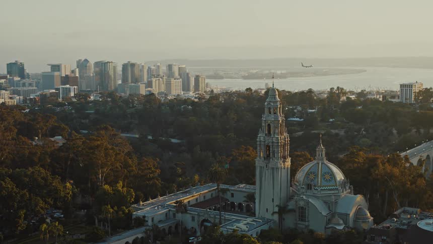 Sunset aerial shot of a plane landing at San Diego Airport with California Tower in foreground