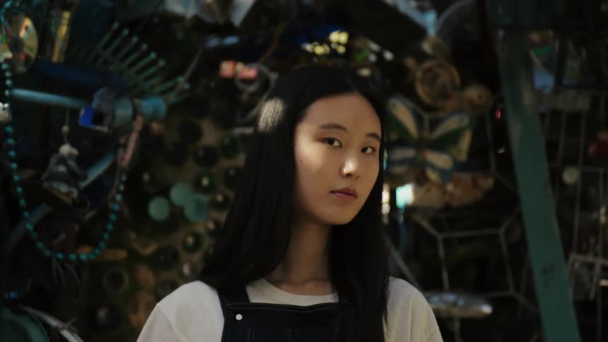 A clip of an asian female posing beside a scrap store