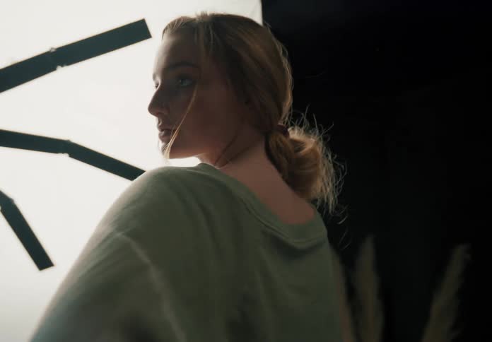 A young woman posing for a photo in front of a large light before laughing and smiling