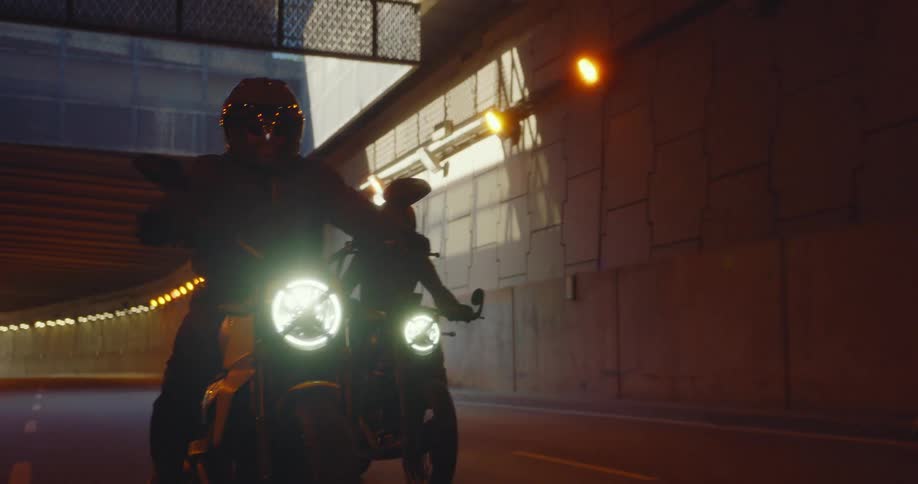Three bikers going through an underpass on a freeway