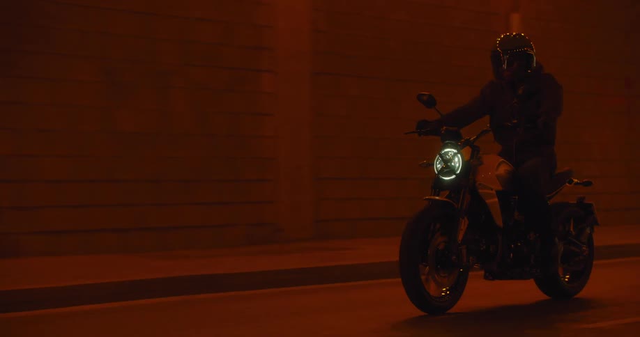 A person riding a motorcycle wearing a helmet riding down the road at night