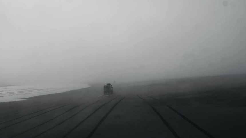 Suv rolling along a beach on a very overcast day