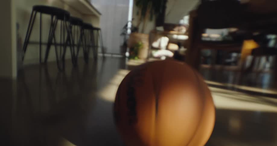 A basketball rolls through the dining room and hits the stools set up at the kitchen bar