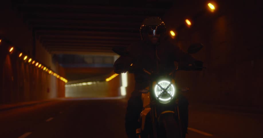 Male motorcyclist rides through a tunnel passing under an overpass