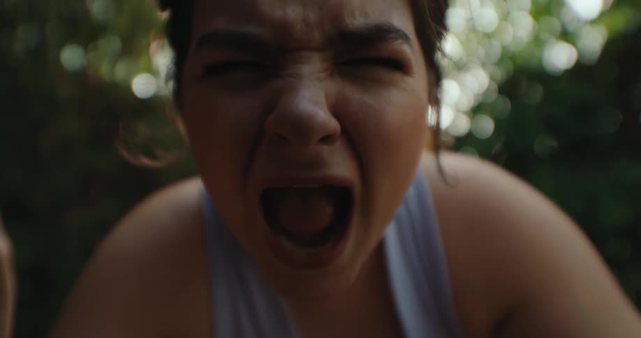 The face of a young woman who opens her mouth and closes her eyes and screams