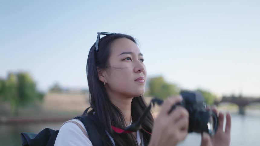 Close up of a woman holding a camera up to her face taking a picture before taking it down from her face out in the open