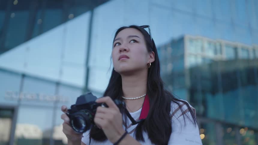A tourists takes pictures of the large buildings