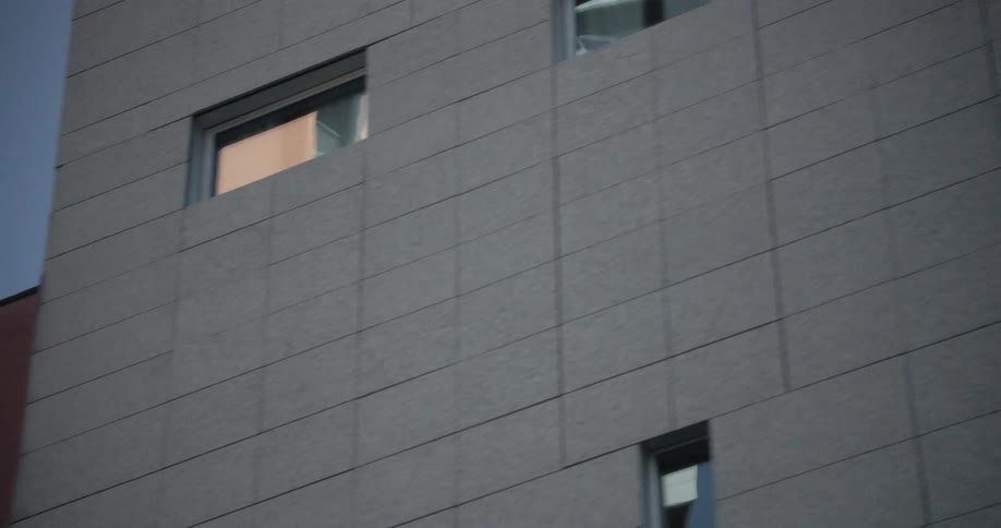 Closeup view of a modern building facade with large glass windows reflecting the sky