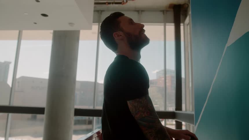 Male artist uses a lift to reach the level of a painting hung near the ceiling in a tall room