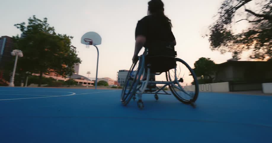 A teenager is playing basketball in a wheelchair