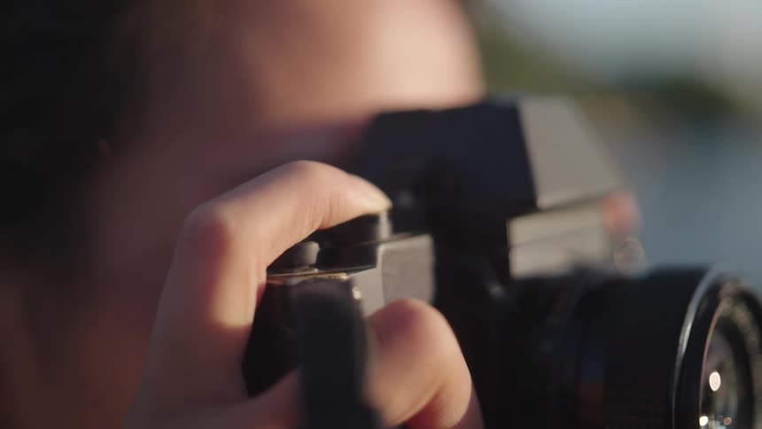 Extreme close up of a woman holding a camera pressing the capture button on the top